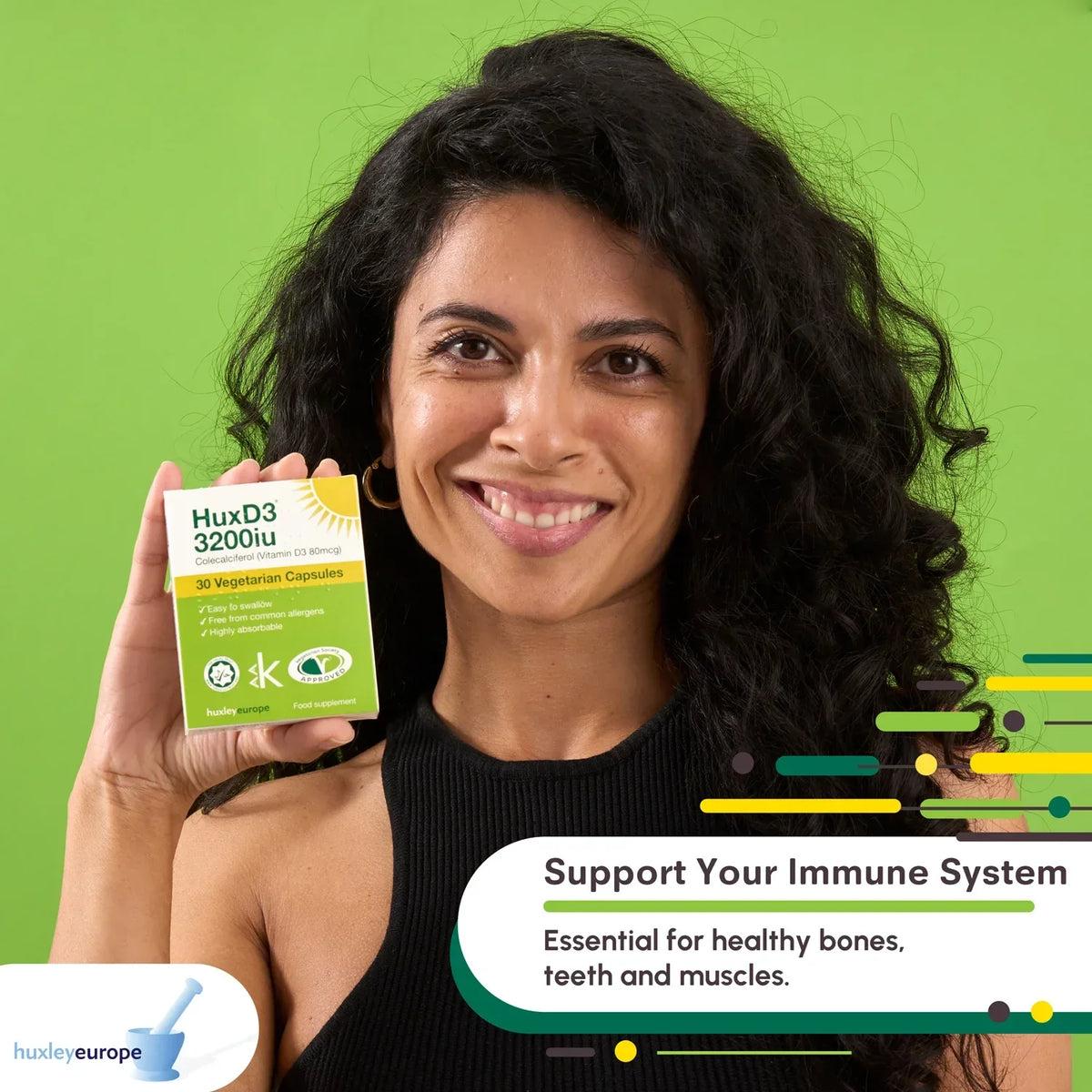 A smiling woman holding a bottle of HuxD3 3200iu Vitamin D3 vegetarian capsules against a green background.