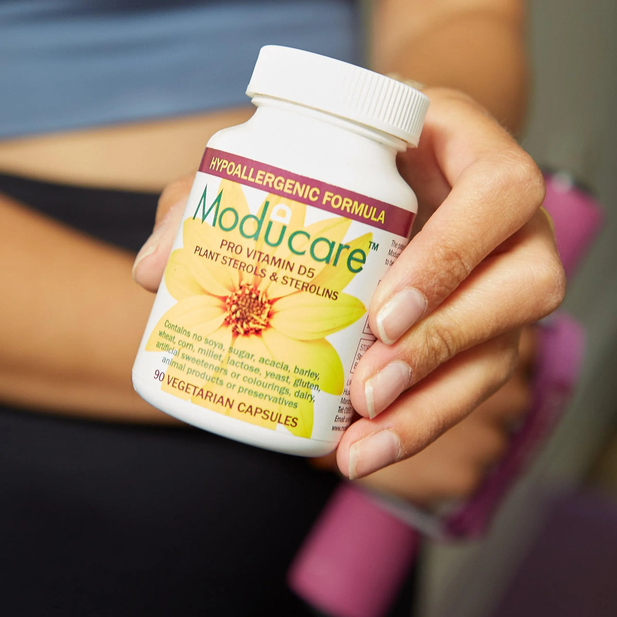 Hand holding Moducare Pro Vitamin D3 with plant sterols and sterolins supplement capsules.